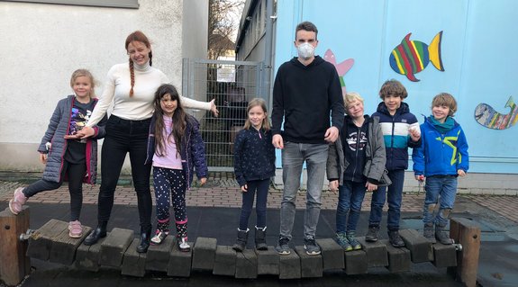 sechs Kinder und zwei Studierende der katho NRW stehen in einer Reihe nebeneinander und lächeln in die Kamera