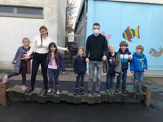 sechs Kinder und zwei Studierende der katho NRW stehen in einer Reihe nebeneinander und lächeln in die Kamera