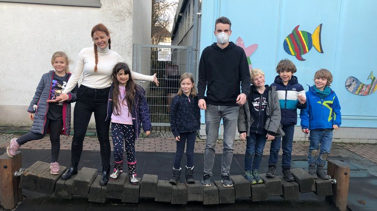 sechs Kinder und zwei Studierende der katho NRW stehen in einer Reihe nebeneinander und lächeln in die Kamera
